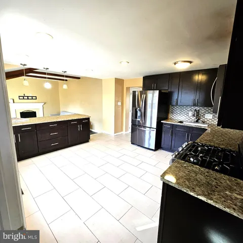 a kitchen with stainless steel appliances kitchen island granite countertop a refrigerator and a stove top oven