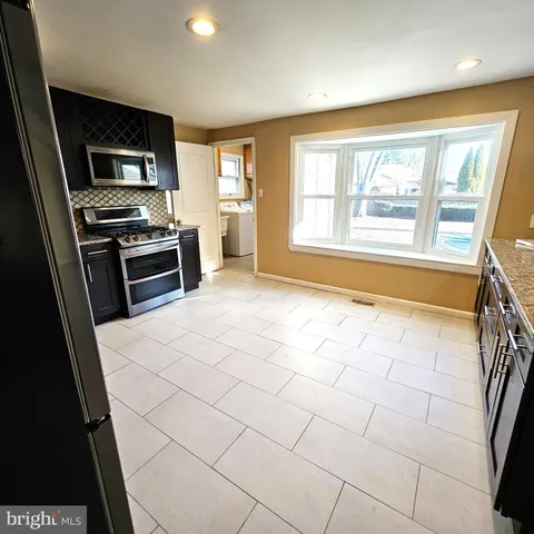 a large kitchen with stainless steel appliances a stove a sink and a microwave