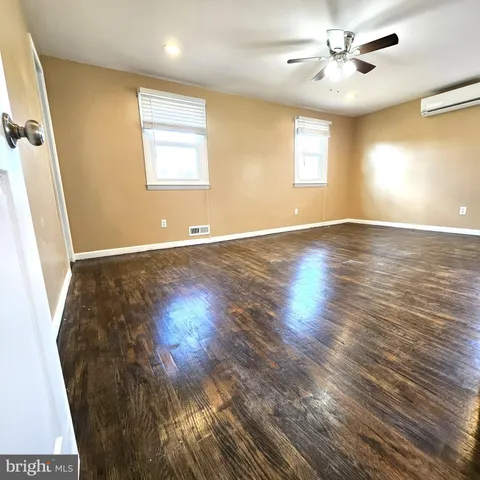 a view of an empty room with window and wooden floor