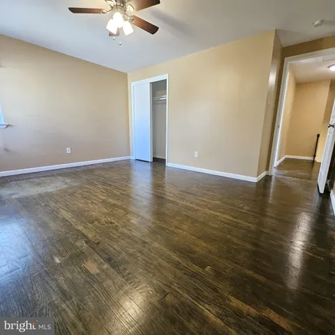 an empty room with wooden floor and fan
