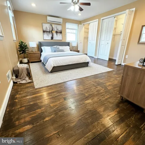 a spacious bedroom with a bed and wooden floor