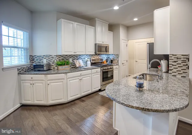a kitchen with stainless steel appliances granite countertop a sink a microwave and refrigerator