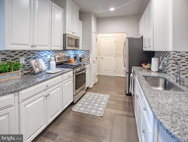 a kitchen with granite countertop a sink stove and refrigerator