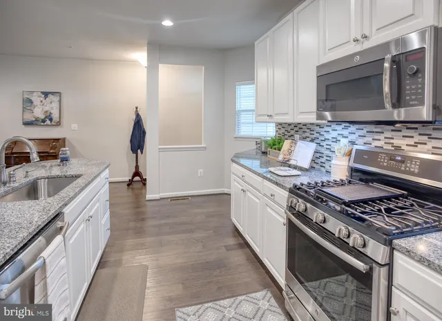 a kitchen with stainless steel appliances granite countertop a stove a sink and a microwave