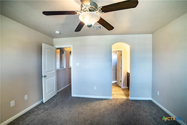 an empty room with a chandelier fan and windows