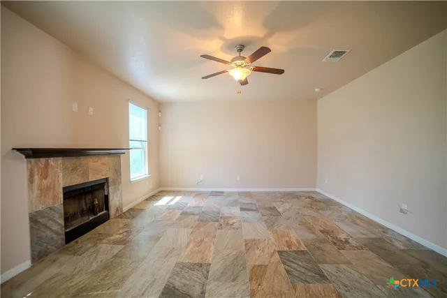 a view of empty room with fireplace and fan