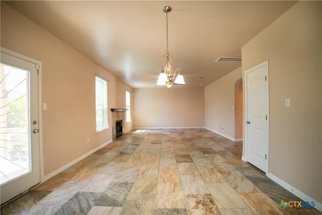 a view of a livingroom with a chandelier fan and kitchen view