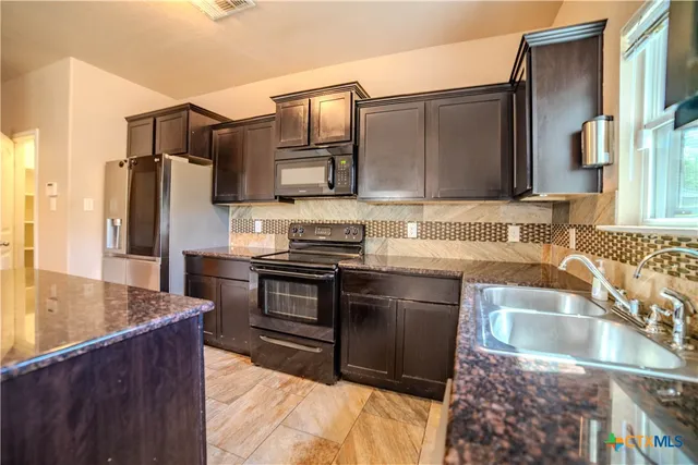 a kitchen with stainless steel appliances granite countertop a sink stove and refrigerator