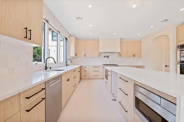 a large white kitchen with stainless steel appliances sink and cabinets