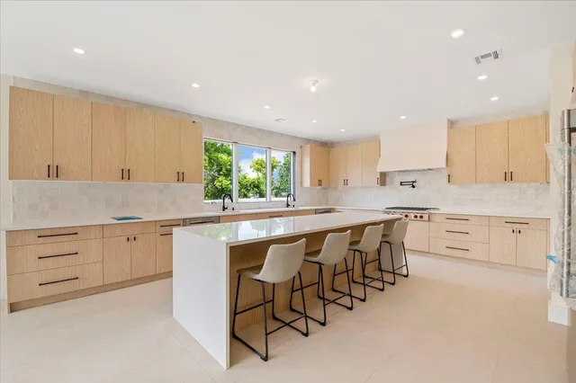 a kitchen with granite countertop white cabinets stainless steel appliances with a dining table and chairs