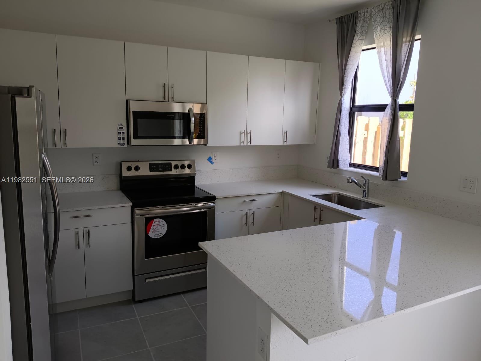 13262 Southwest 285th Street Homestead, FL 33033 - Photo 4 of 16 a kitchen with a stove a sink and a microwave