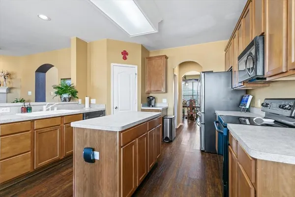 a kitchen with stainless steel appliances granite countertop a stove top oven a sink dishwasher a dining table and chairs with wooden floor
