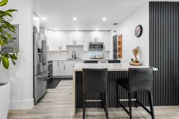 a kitchen with kitchen island granite countertop a sink a counter top space stainless steel appliances and cabinets