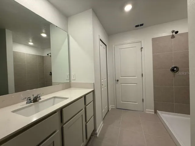 a bathroom with a sink double vanity granite tub shower and a mirror