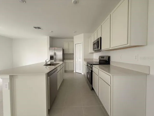 a kitchen with stainless steel appliances granite countertop a sink and dishwasher a stove top oven with white cabinets
