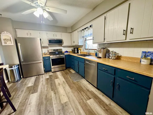 a kitchen with stainless steel appliances granite countertop a refrigerator a sink dishwasher a stove with wooden cabinets and floor