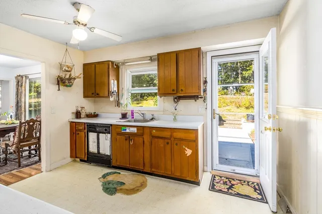 a kitchen with stainless steel appliances granite countertop a stove a sink dishwasher and white cabinets with wooden floor