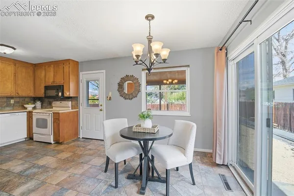 a kitchen with a refrigerator a stove cabinets dining table and chairs