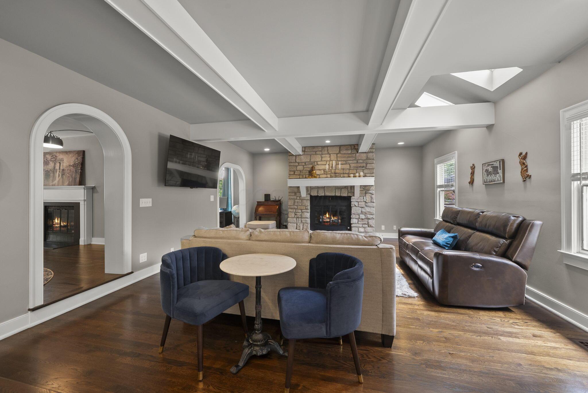 1851 Berkshire Road Columbus, OH 43221 - Photo 19 of 125 Step down family room with elevated coffered ceilings, warm hardwood floors, gas fireplace and mantle with stone hearth, lit with skylights and architectural detail curved doorways.