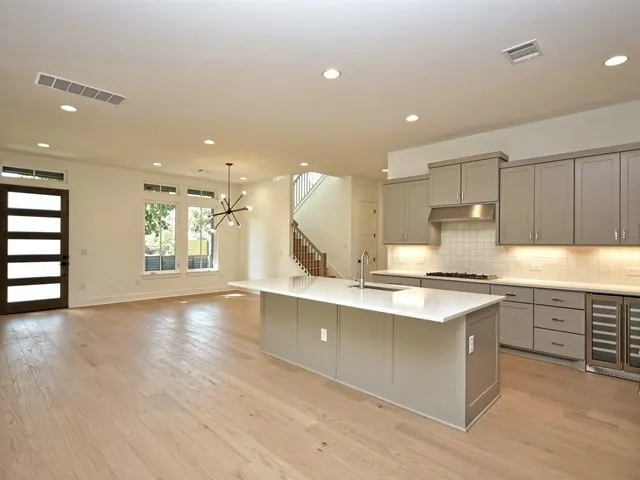 a kitchen with stainless steel appliances granite countertop a stove top oven a sink dishwasher and a refrigerator with wooden floor