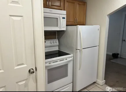 a white refrigerator freezer and a stove sitting inside of a kitchen