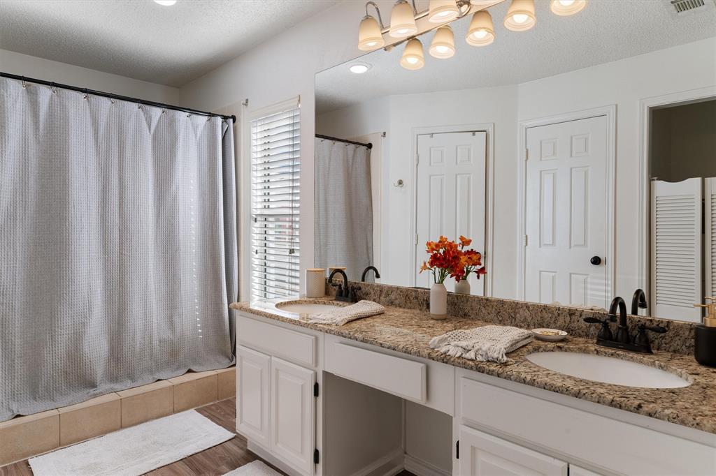 7518 Bayview Drive Rowlett, TX 75088 - Photo 15 of 22 Bathroom with double vanity, a textured ceiling, light wood finished floors, tiled shower / bath combo, and a closet