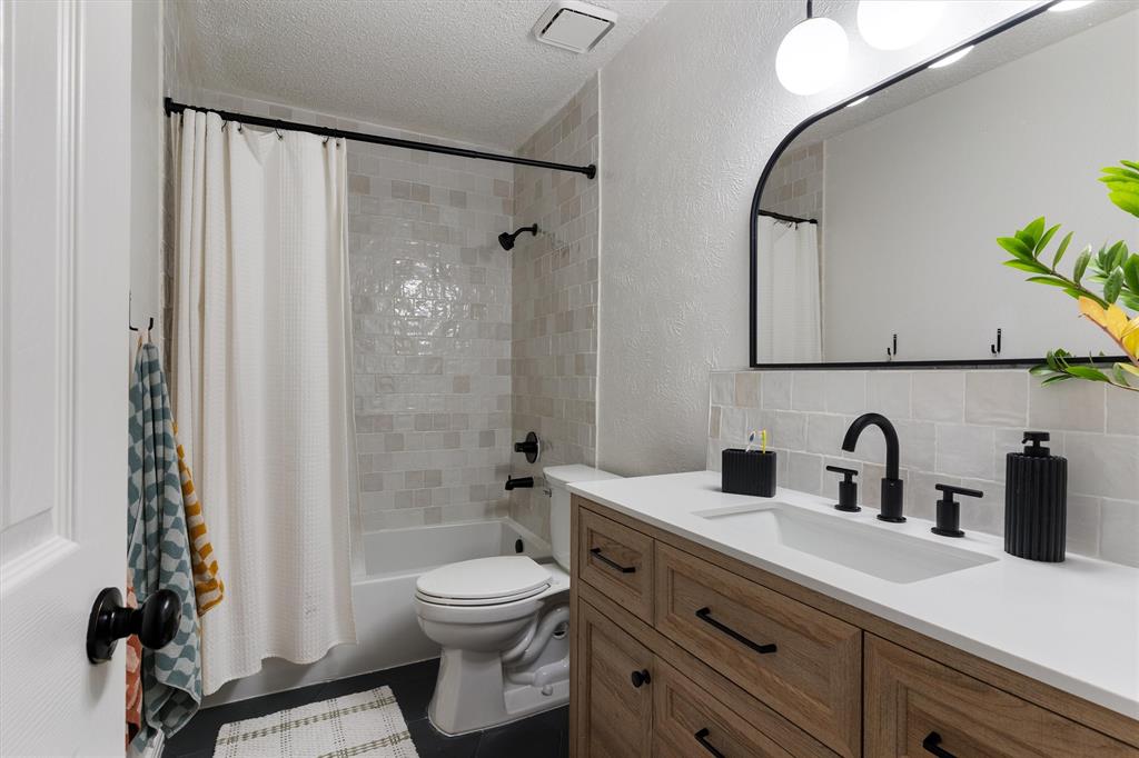 7518 Bayview Drive Rowlett, TX 75088 - Photo 17 of 22 Full bath with a textured wall, a textured ceiling, shower / bath combination with curtain, vanity, and backsplash