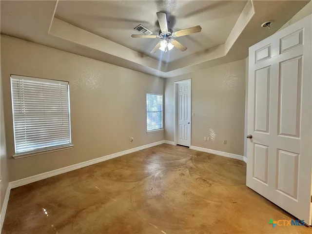 an empty room with windows and fan