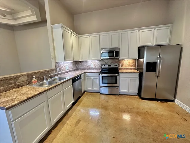 a kitchen with granite countertop a sink and stainless steel appliances