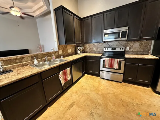 a kitchen with stainless steel appliances granite countertop a stove a sink and a microwave
