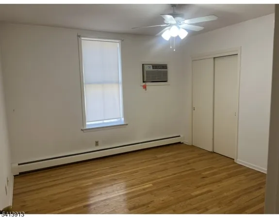 a view of an empty room with window and chandelier fan