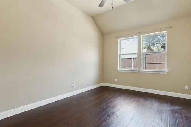 an empty room with wooden floor and a ceiling fan