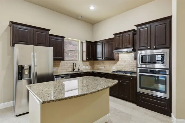 a kitchen with stainless steel appliances granite countertop a sink a stove a refrigerator and island