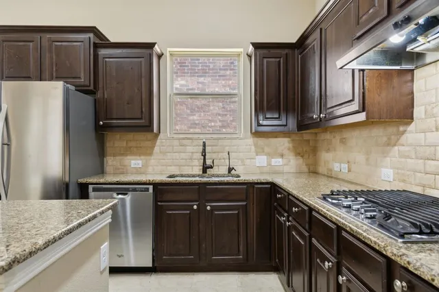 a kitchen with granite countertop a sink and refrigerator
