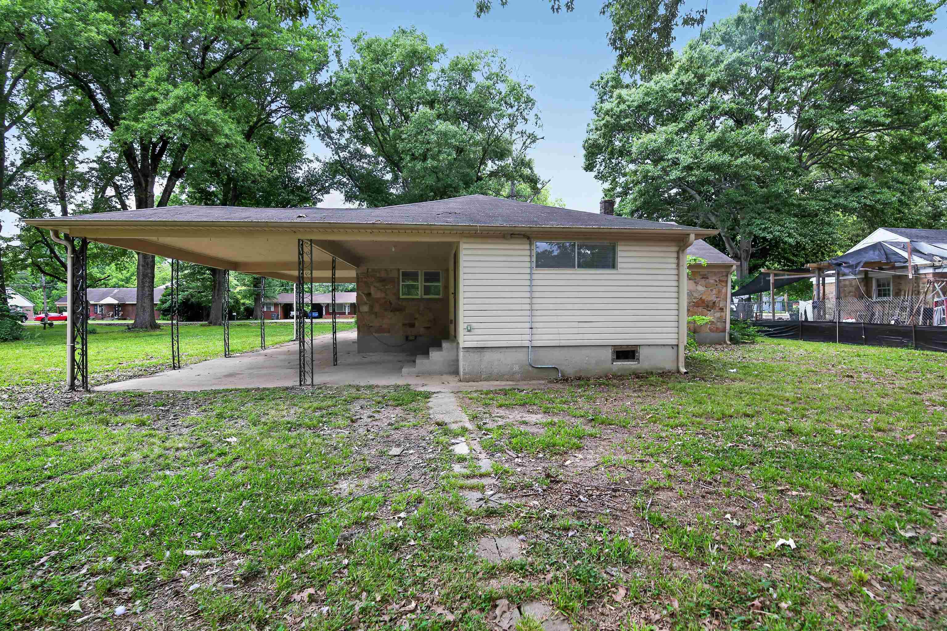 2840 Allen Road Memphis, TN 38128 - Photo 4 of 31 Rear exterior featuring a covered carport with decorative metal supports, a concrete patio, and a stone facade section