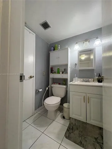 a bathroom with a toilet sink vanity and mirror