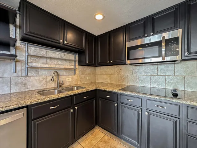 a kitchen with granite countertop stainless steel appliances wooden cabinets and a sink