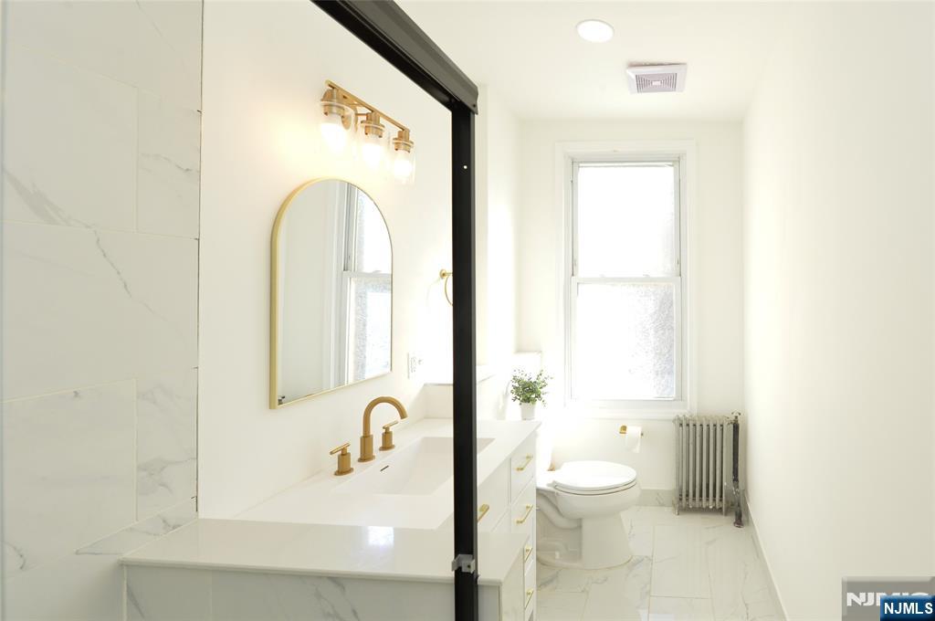 209 Adams Street, Unit 5 Hoboken, NJ 07030 - Photo 6 of 15 a bathroom with a toilet a sink and a bathtub