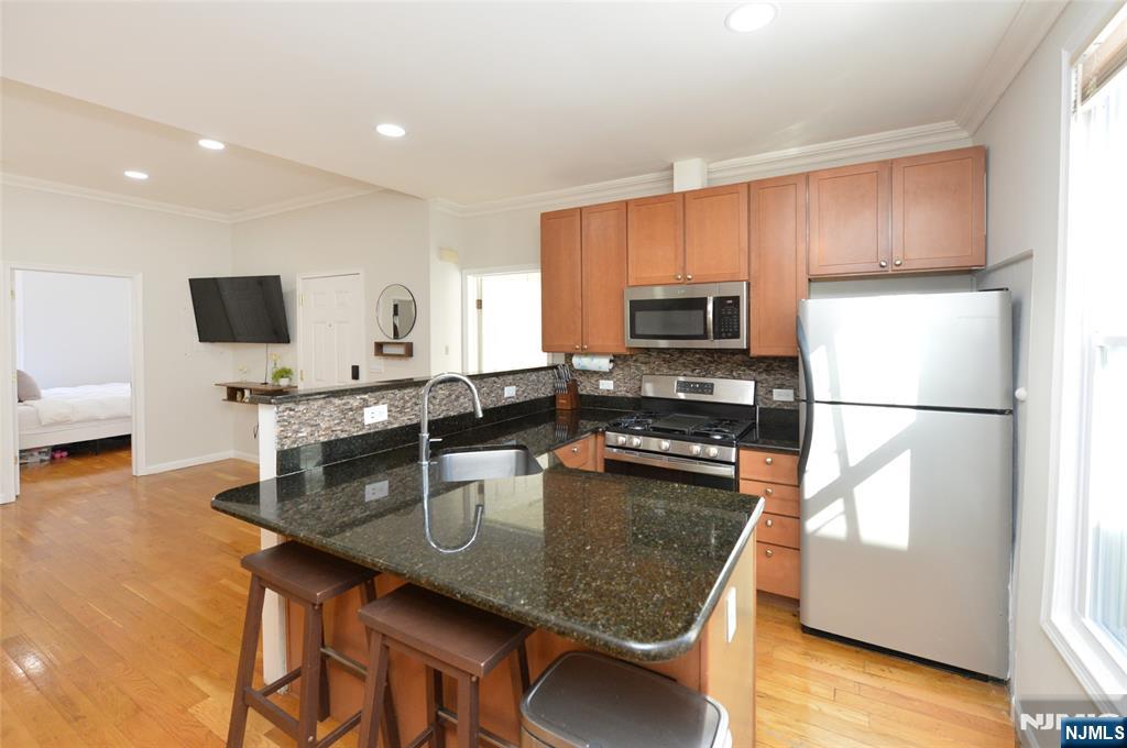 209 Adams Street, Unit 5 Hoboken, NJ 07030 - Photo 8 of 15 a kitchen with kitchen island a counter space a sink and appliances