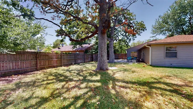 a view of backyard with wooden fence and a large tree