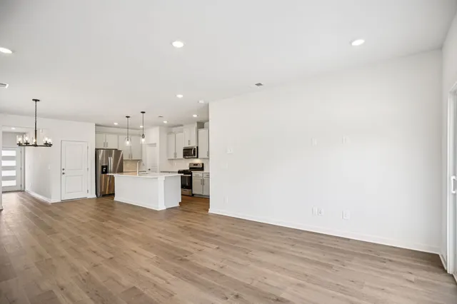 a view of kitchen with kitchen island refrigerator sink and white cabinets with wooden floor