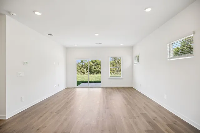 an empty room with wooden floor and window