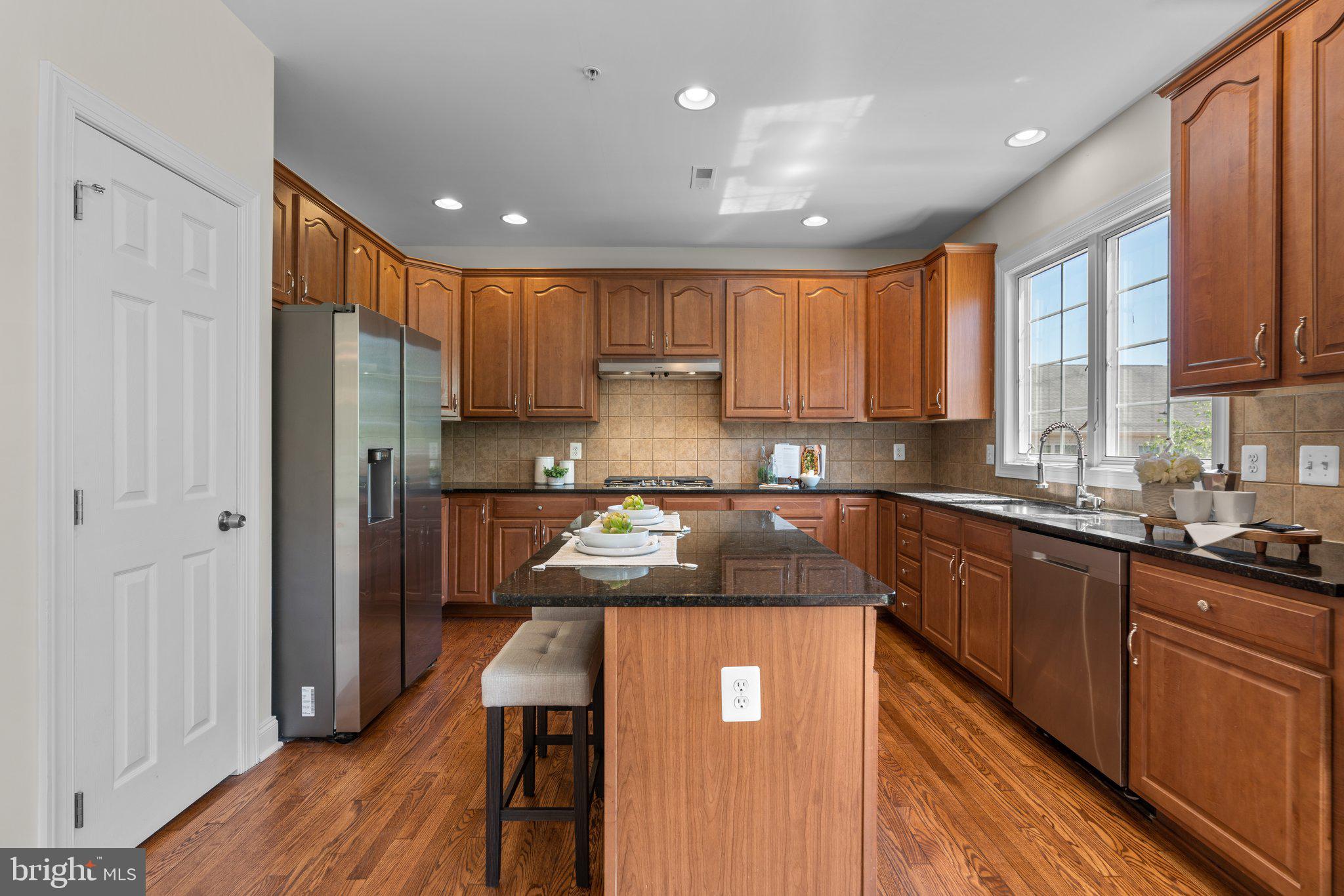 22104 Ginger Tree Way Clarksburg, MD 20871 - Photo 11 of 57 a kitchen with a refrigerator a sink and wooden cabinets