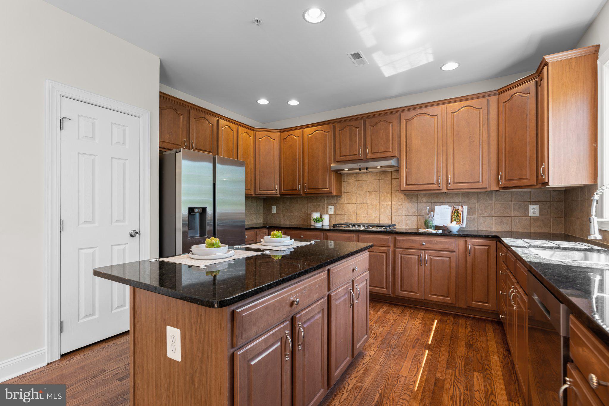 22104 Ginger Tree Way Clarksburg, MD 20871 - Photo 12 of 57 a kitchen with kitchen island granite countertop a sink stove and refrigerator