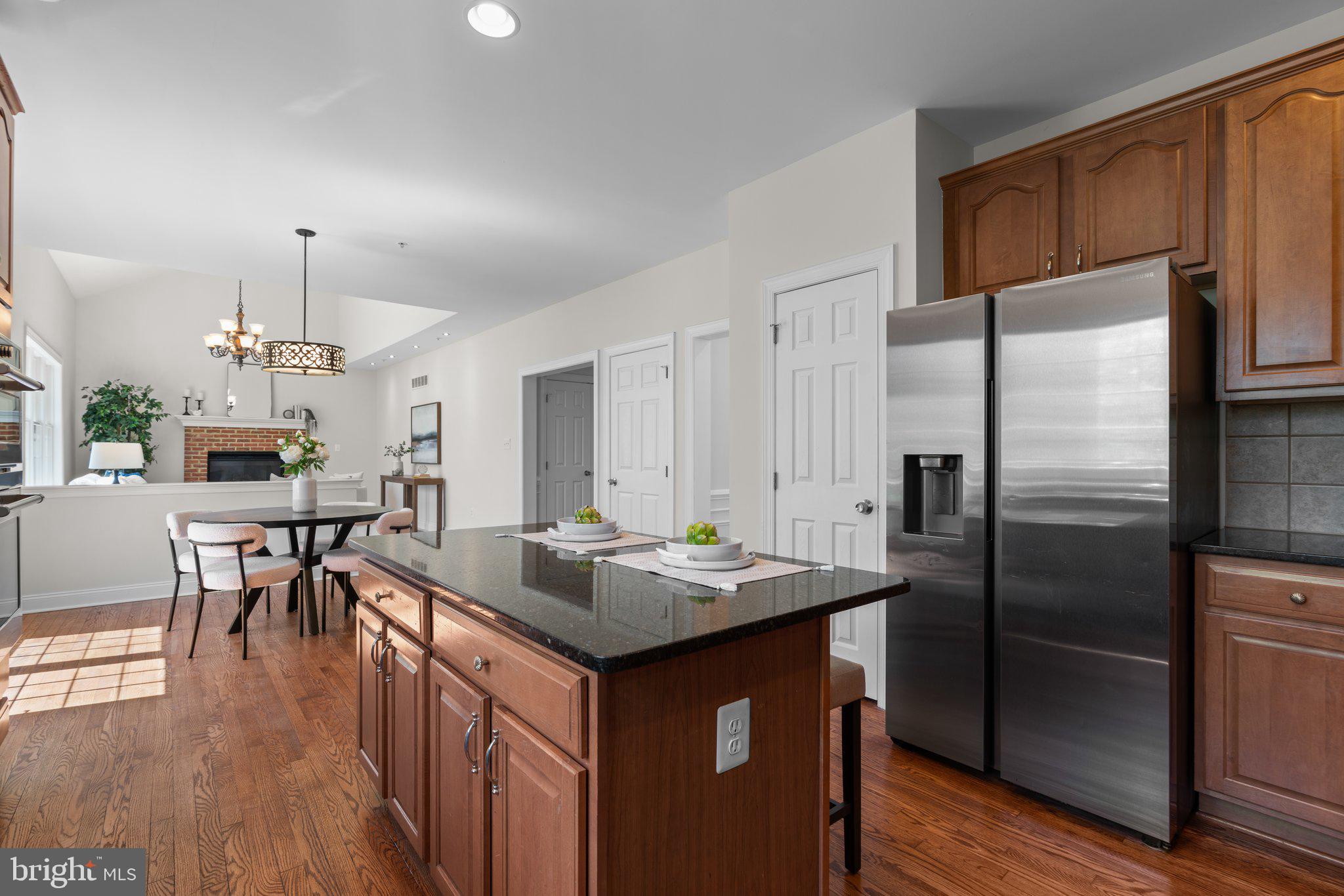 22104 Ginger Tree Way Clarksburg, MD 20871 - Photo 14 of 57 a kitchen with stainless steel appliances granite countertop a refrigerator a stove a sink a dining table and chairs with wooden floor