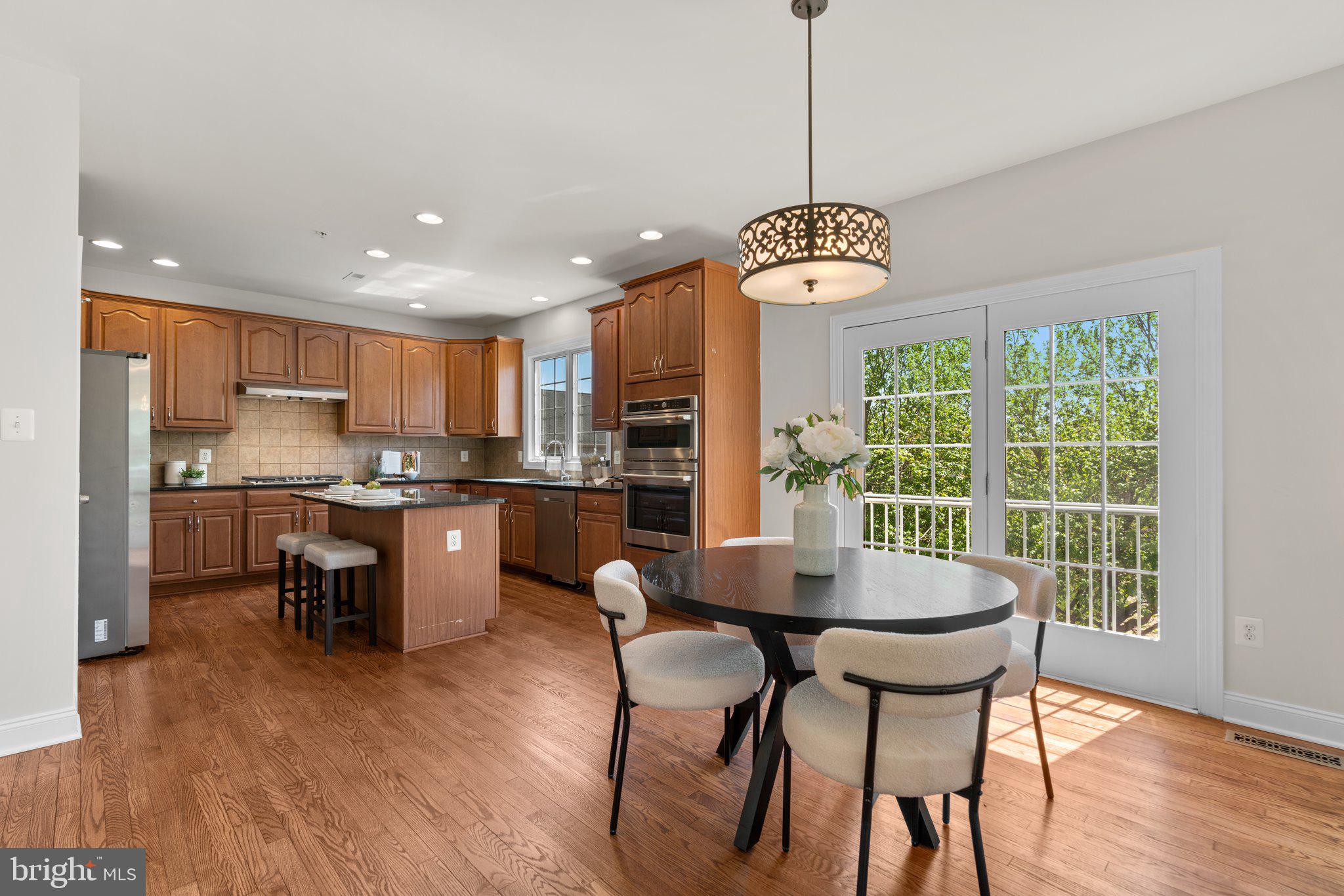 22104 Ginger Tree Way Clarksburg, MD 20871 - Photo 17 of 57 a kitchen with a dining table chairs stainless steel appliances and cabinets