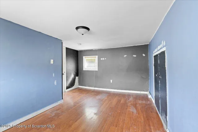 a view of an empty room with wooden floor and a bathroom