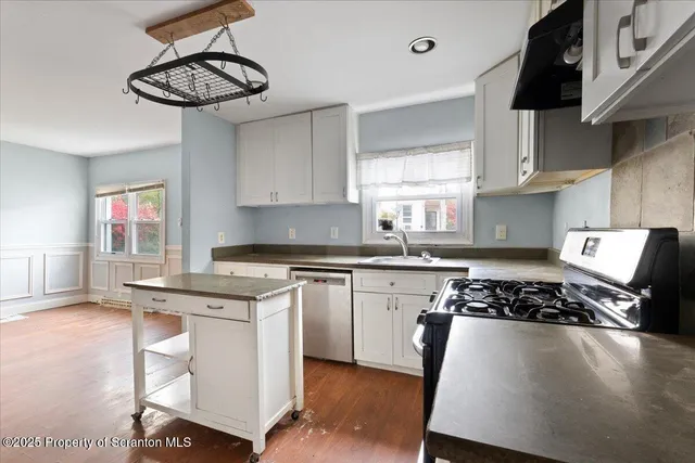 a kitchen with stainless steel appliances a sink a stove and white cabinets