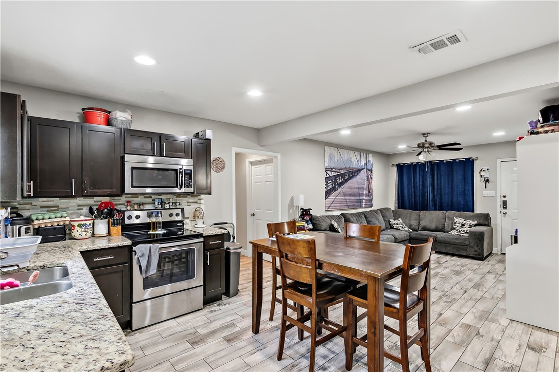 112 Ehlinger Drive Bryan, TX 77801 - Photo 11 of 18 a kitchen with stainless steel appliances granite countertop a stove top oven a sink dishwasher a dining table and chairs with wooden floor