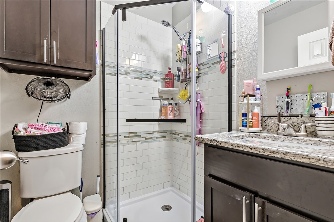 112 Ehlinger Drive Bryan, TX 77801 - Photo 16 of 18 a bathroom with a granite countertop sink a toilet and a shower
